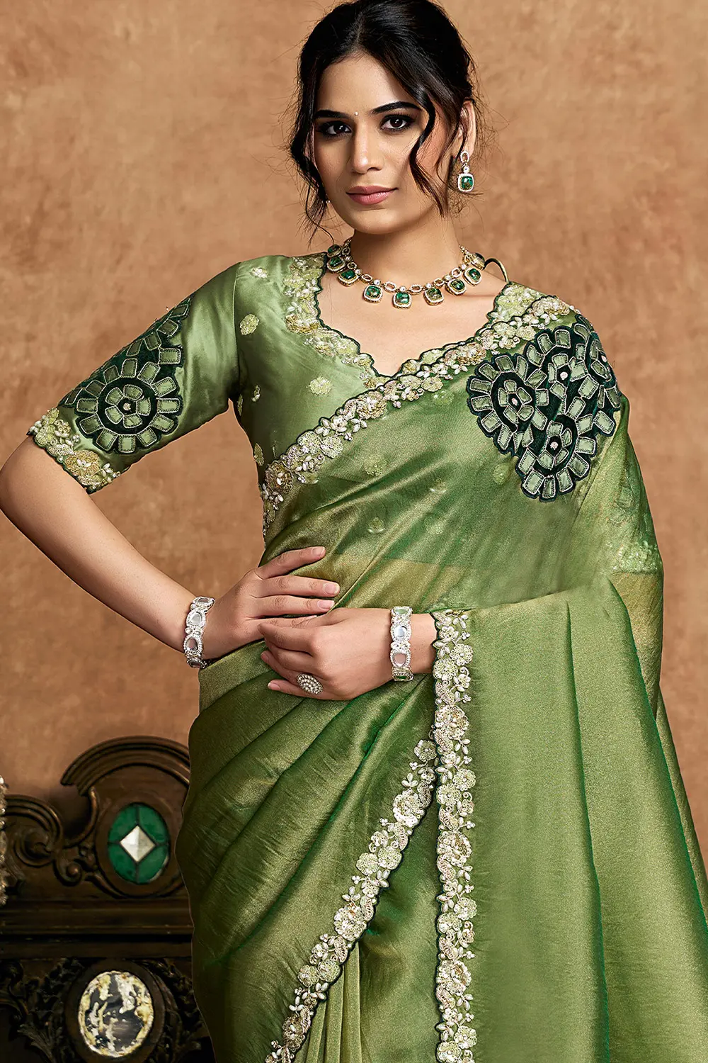 Close-up of intricate stone and applique work on green saree