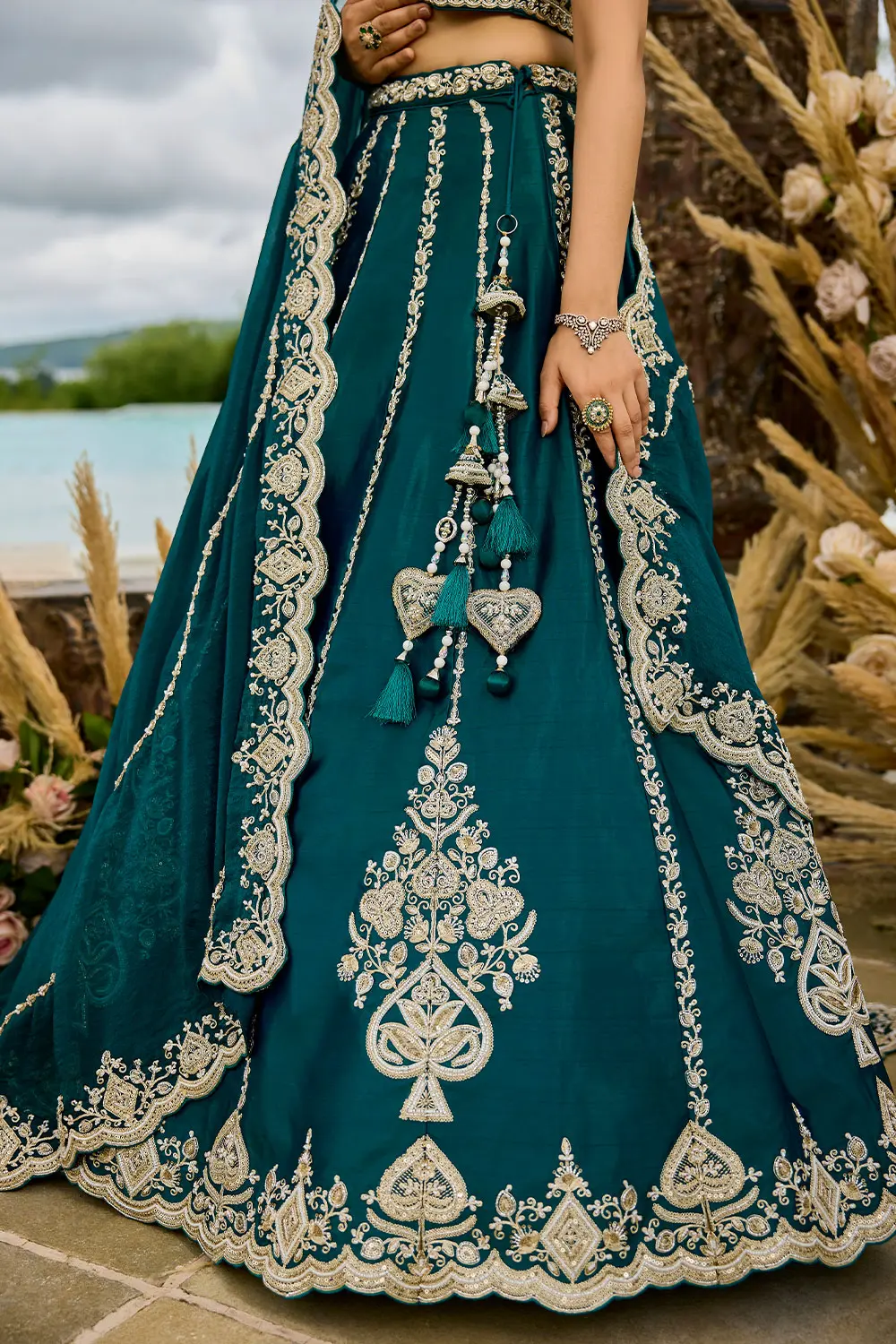 Teal blue lehenga draped on mannequin with silver jewelry styling