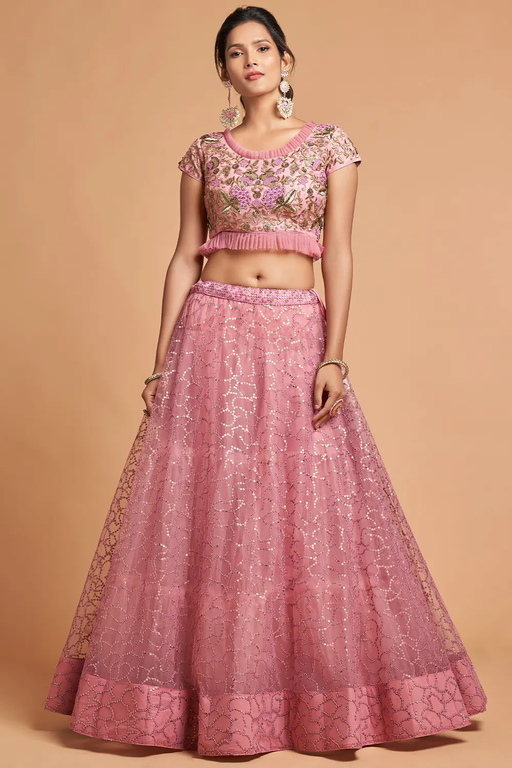 A plus-size model smiling and twirling in the Dusty Pink Net Lehenga, showcasing the comfortable fit.