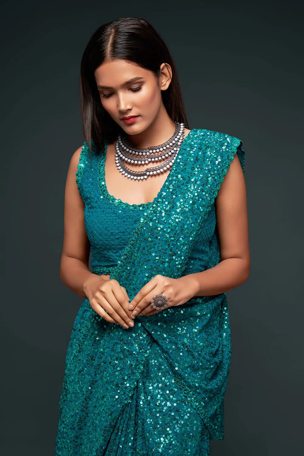 Close up of thread embroidery and multiple sequins on teal blue saree