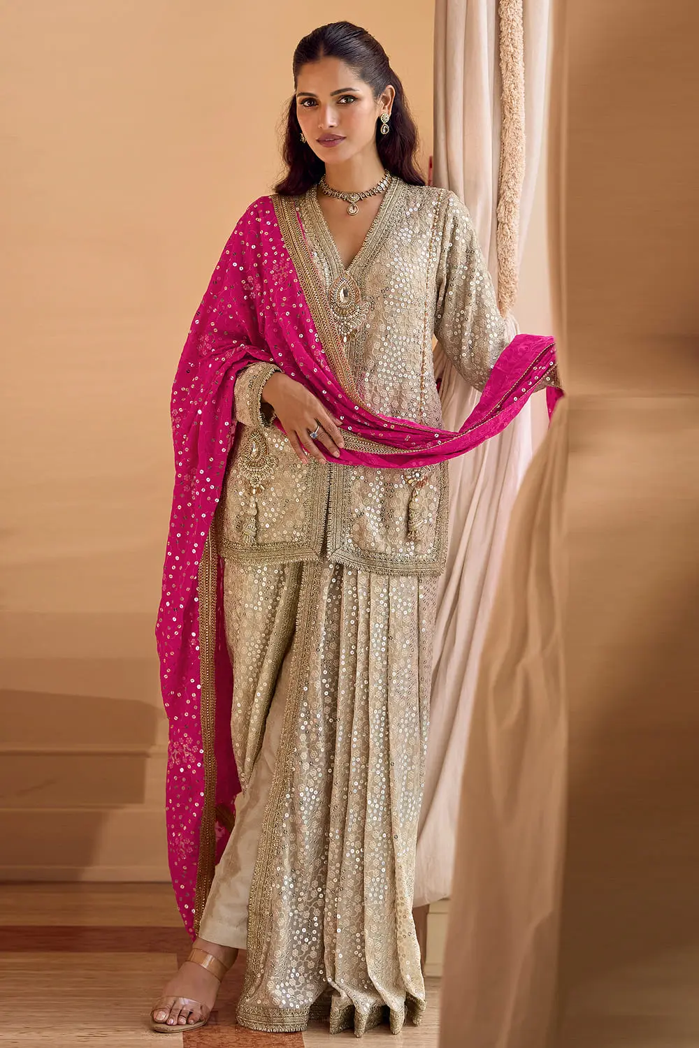 Front view of premium georgette dhoti suit with dupatta in beige and hot pink featuring heavy embroidered hand work.