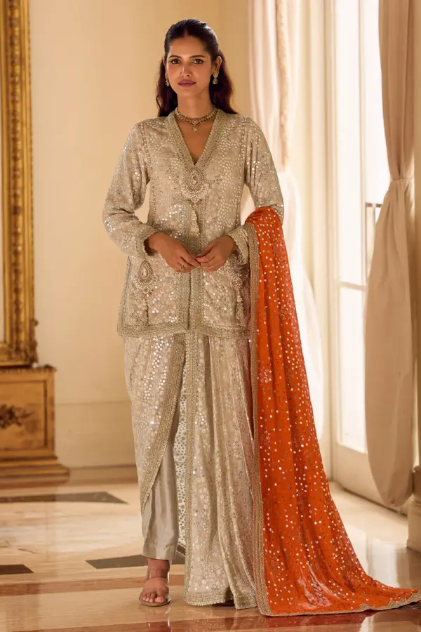 Flawless beige embroidered georgette dhoti suit with dupatta featuring a vibrant orange drape.