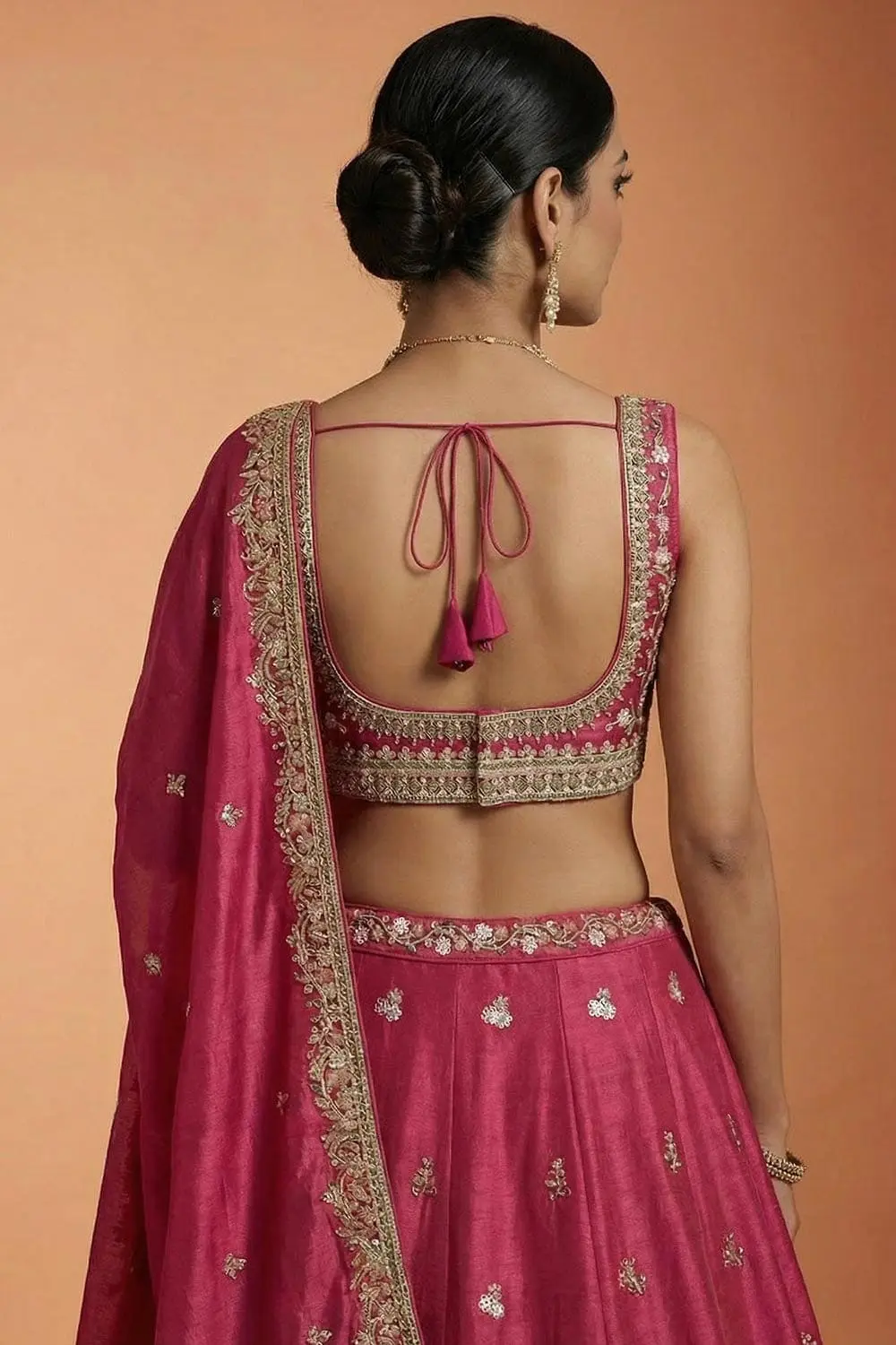 Rear view showing the pink blouse's V-neck cut and the dupatta's taping border