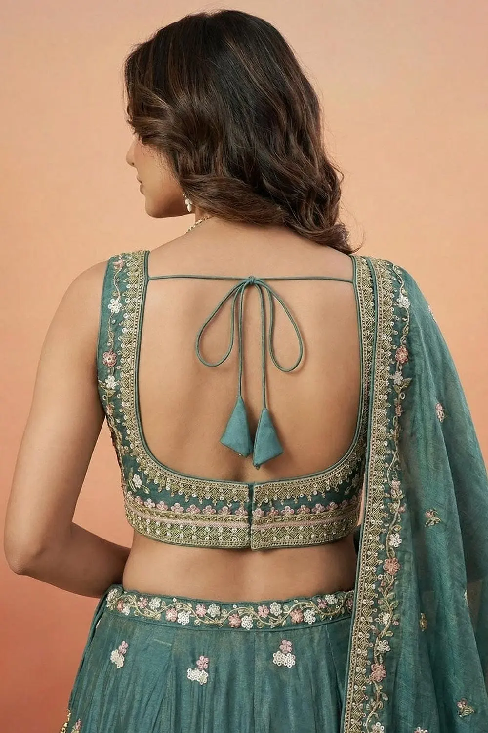 Three-quarter sleeve and shoulder embroidery seen from behind on the teal blouse